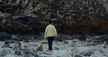 A man in a yellow sweater standing on rocks video