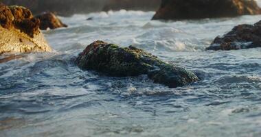 A rock in the ocean with waves crashing over it video