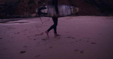 A person walking on a beach with a surfboard video