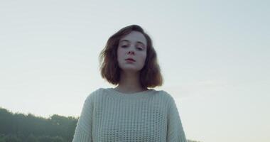 A woman in a sweater standing in front of a field video