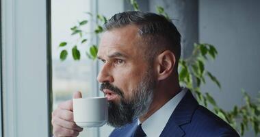 A man in a suit drinking coffee from a mug video
