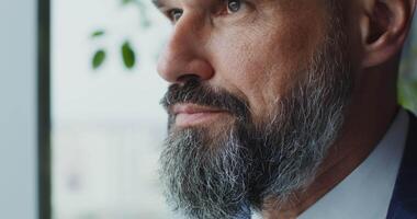 A man with a beard and a suit looking out the window video