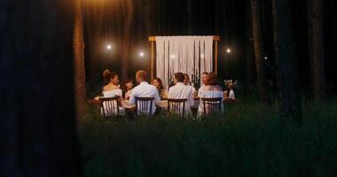 A group of people sitting at a table in the woods video