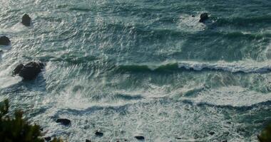 A view of the ocean from above with waves crashing into the rocks video