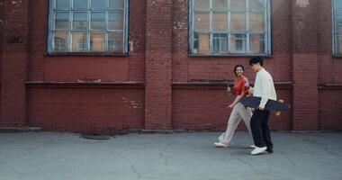 A man and woman walking in front of a building with a skateboard video