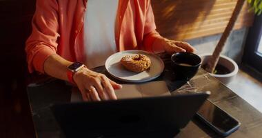 A woman is sitting at a table with a cup of coffee and a donut video
