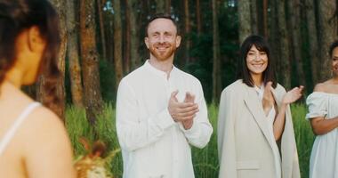 A man and woman in white are standing in a forest video
