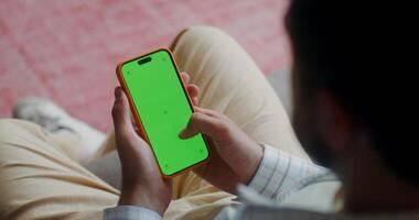 Man using smartphone with green screen at home video