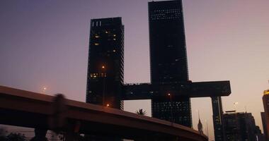 from a moving car, a view of skyscrapers with light in the windows in the rays of the setting sun video