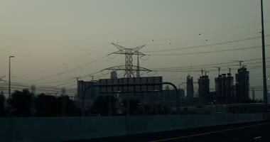 A busy highway on the outskirts of a modern metropolis with glass skyscrapers and many buildings under construction. Power lines above the road video