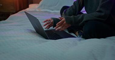 A woman is using a laptop while sitting on the bed. Close-up of a laptop, the woman's face is not visible video