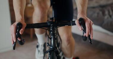 Close-up of male hands on the handlebars of a bicycle during indoor training on a cycling simulator, no face, unrecognizable person video