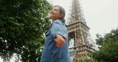 A woman in a denim jacket is standing in front of the eiffel tower video