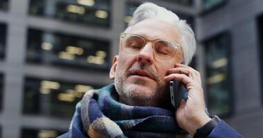 A man in glasses and a scarf talking on a cell phone video