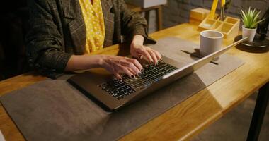 Woman with nails painted with black varnish, typing on a laptop while sitting at a table in the office, close-up, the woman's face is not visible video