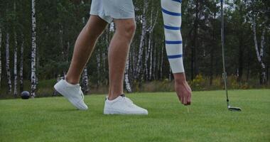 Preparing for the game of golf, placing the ball with a stand on the lawn. Unrecognizable man about to play golf, golf ball close up video