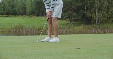 A young man hits the ball with a golf club, trying to get into the hole, and having won, he rejoices and goes to get the ball out of the hole with his hand. Close-up of a golf ball hitting a hole video