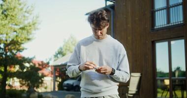 A man in a sweatshirt is looking at his cell phone video