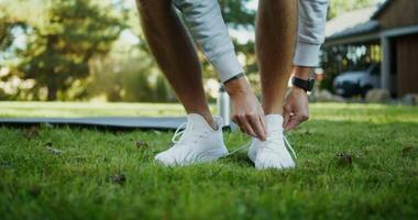 A man tying his shoes on a grassy field video