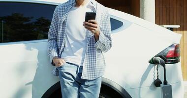 Man using smartphone while charging electric car video