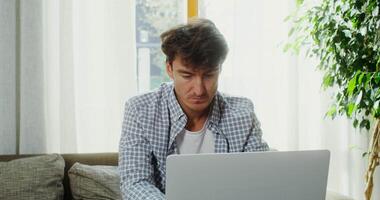 A man sitting on a couch with a laptop video