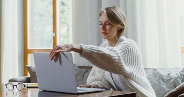 A woman in a sweater is using a laptop video