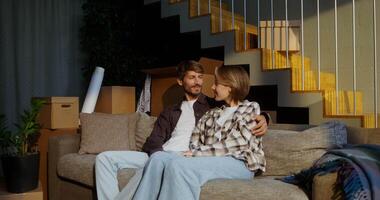 A man and woman sitting on a couch in front of boxes video