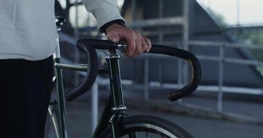 A man holds a bicycle with his hand, an unidentified person, a close-up of a hand on the handlebars of a bicycle video