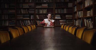 A woman sitting at a table with bookshelves in the background video