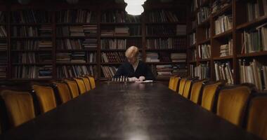 A man sitting at a table in front of a bookcase video