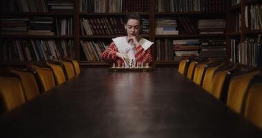 A woman sitting at a table with bookshelves in the background video