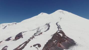 A large snow covered mountain with a person standing on top video