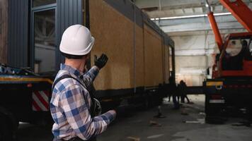 Construction worker supervising prefab home loading process video