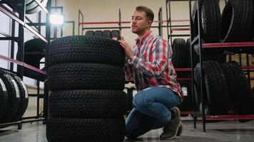 Man inspecting tires and calling a consultant in auto store video