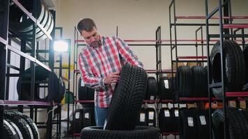 Man inspecting a tire and calling a seller in auto store video