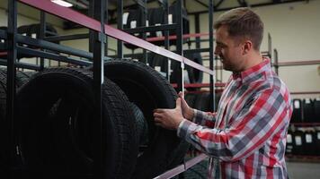 Man selecting a tire from the shelf in auto parts store video