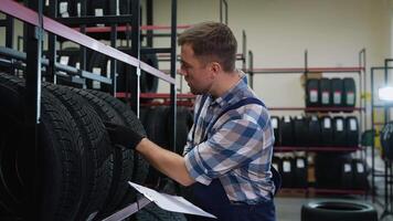 Worker inspecting tires and taking inventory in auto store video