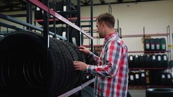 Man examining winter tires on store shelf in auto shop video