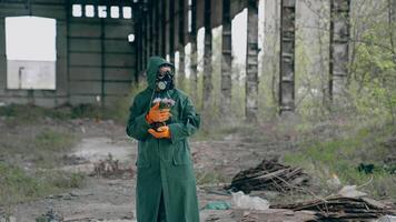 Man in protective uniform and gas mask. Post apocalyptic character with a gun standing in abandoned hangar video