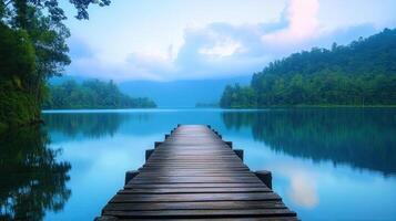 Wooden Pier Extends into the Still Turquoise Waters of a Lake Surrounded by Lush Green Forest Under a Blue Cloudy Sky photo