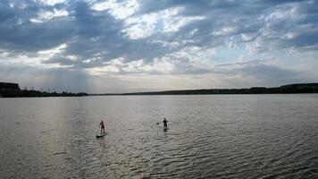 Couple relaxing on paddle sup board. Drone view of couple relaxing on stand up paddle board video