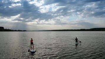 People relaxing on paddle sup board. Aerial view of surfers floating sup board on vacation video