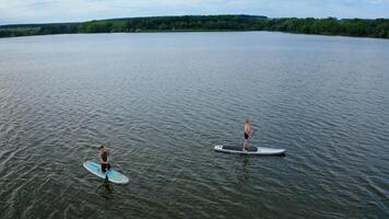 Two Persons On Paddle Board. Drone view of couple on sup paddle boards video