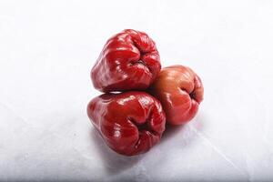 Three red peppers on a white surface photo