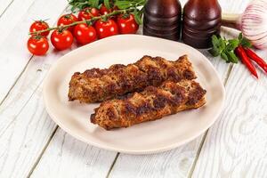 Two meat skewers on a plate with tomatoes and peppers photo