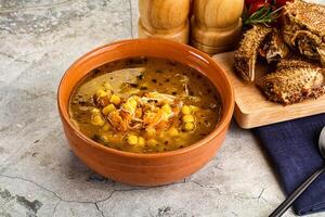 un cuenco de sopa con maíz y un pan en un mesa foto