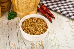 A bowl of mustard seeds on a wooden table photo