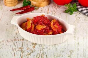 A bowl of tomato sauce on a table next to a knife photo
