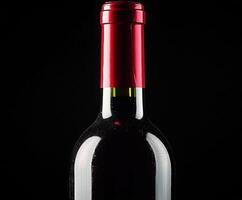 Red wine bottle with shiny cap against black background photo