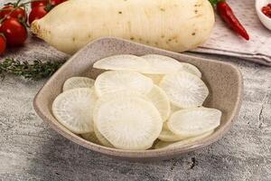 A bowl of sliced white radishes on a table photo